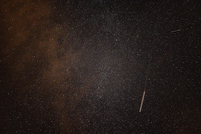 A panoramic shot of a starry sky with a faint, unusual light streak crossing the horizon.