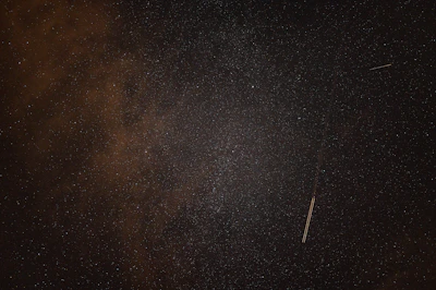 A nighttime photo of a starry sky with a faint, mysterious light streak suggesting a UFO fly-by.