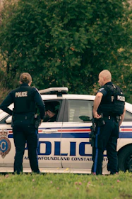 2 police men standing on white police car during daytime