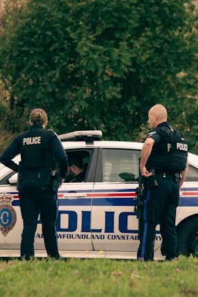 2 police men standing on white police car during daytime
