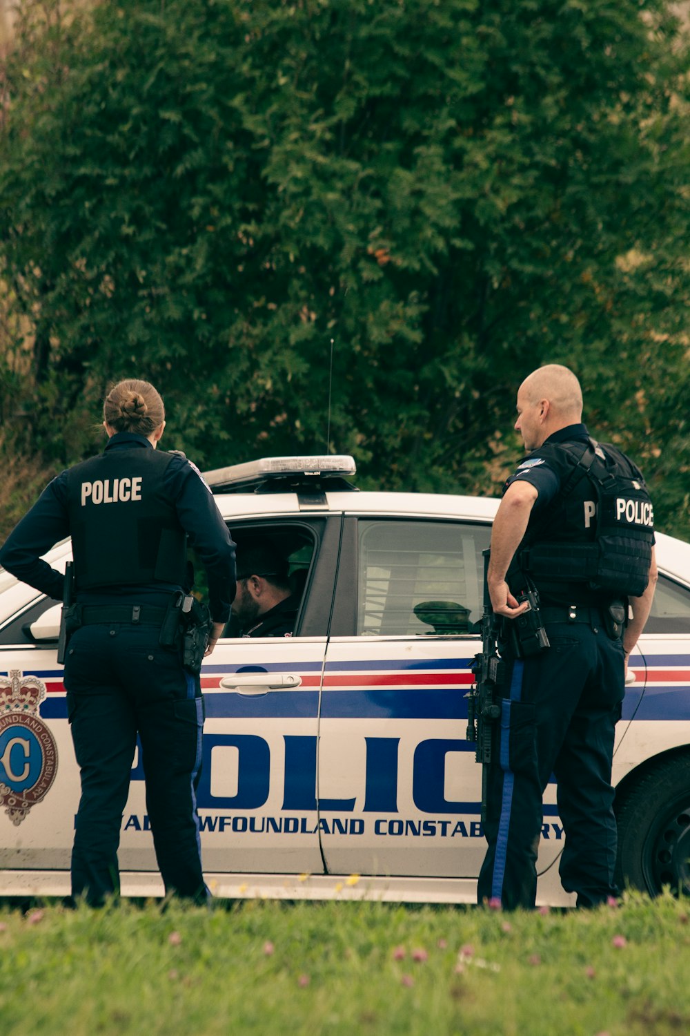 2 policiers debout sur une voiture de police blanche pendant la journée