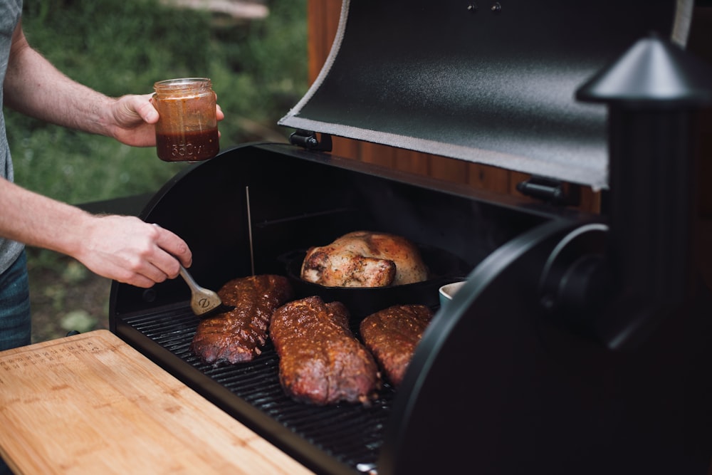 person holding knife slicing meat on black grill