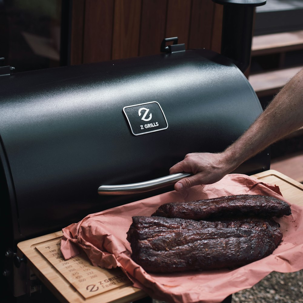 person holding raw meat on brown wooden chopping board