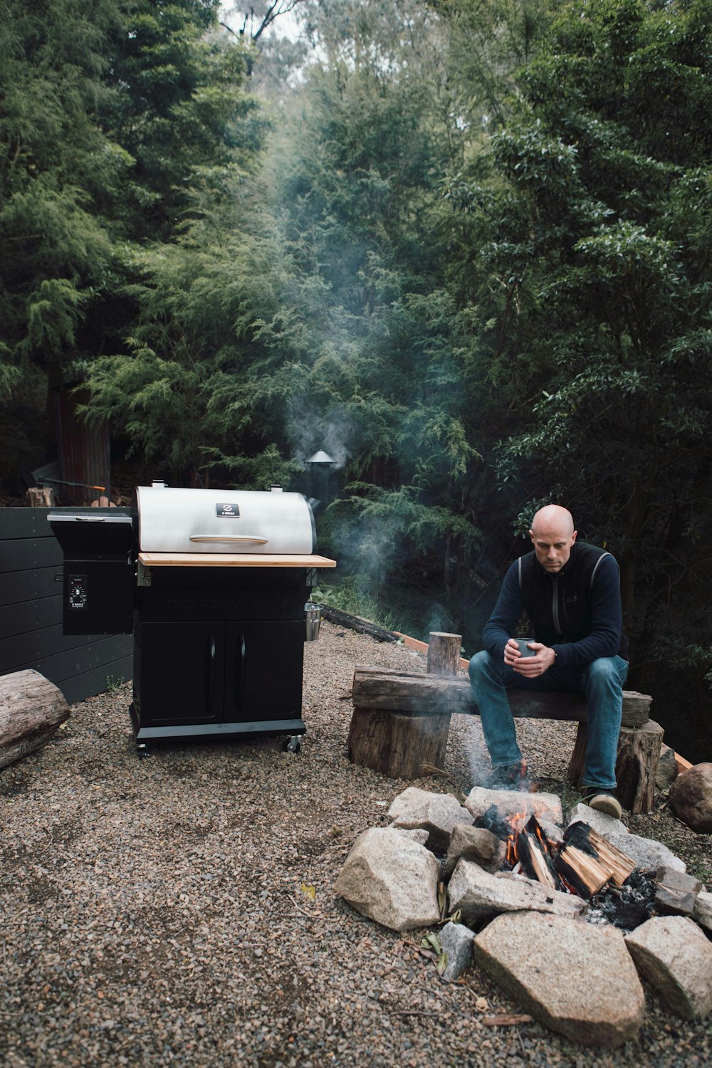 man in blue jacket sitting on brown wooden log