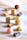 An assortment of uniquely shaped and colored chocolates, each with distinct textures and designs, arranged on a swirling pastel background. The chocolates include geometric shapes, truffles, and textured pieces.