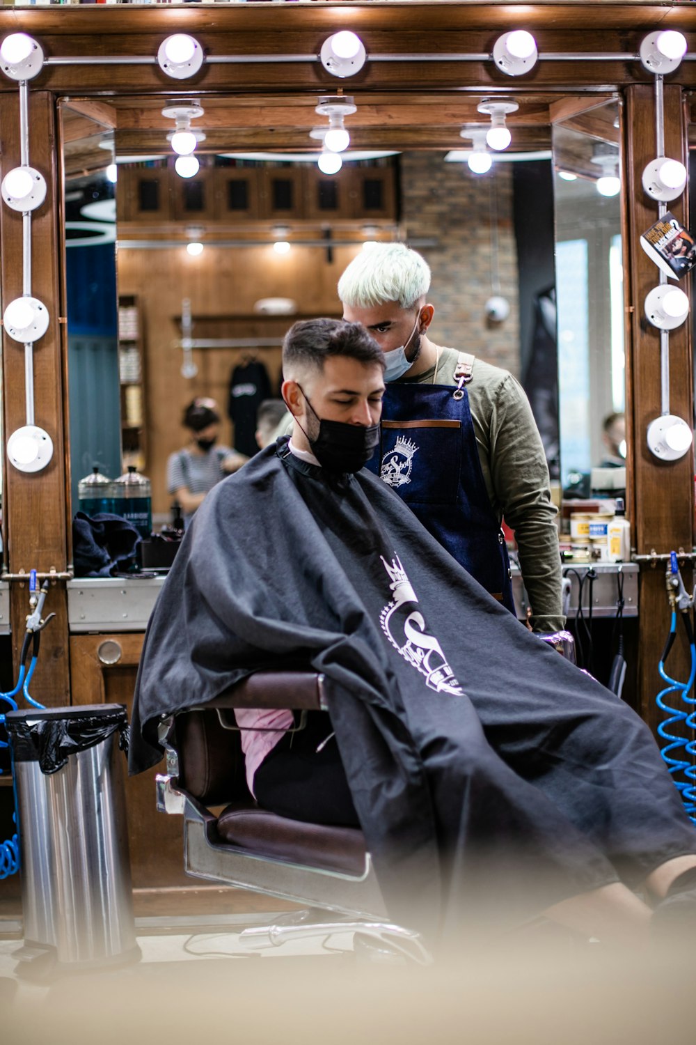 man in black and gray jacket sitting on barber chair