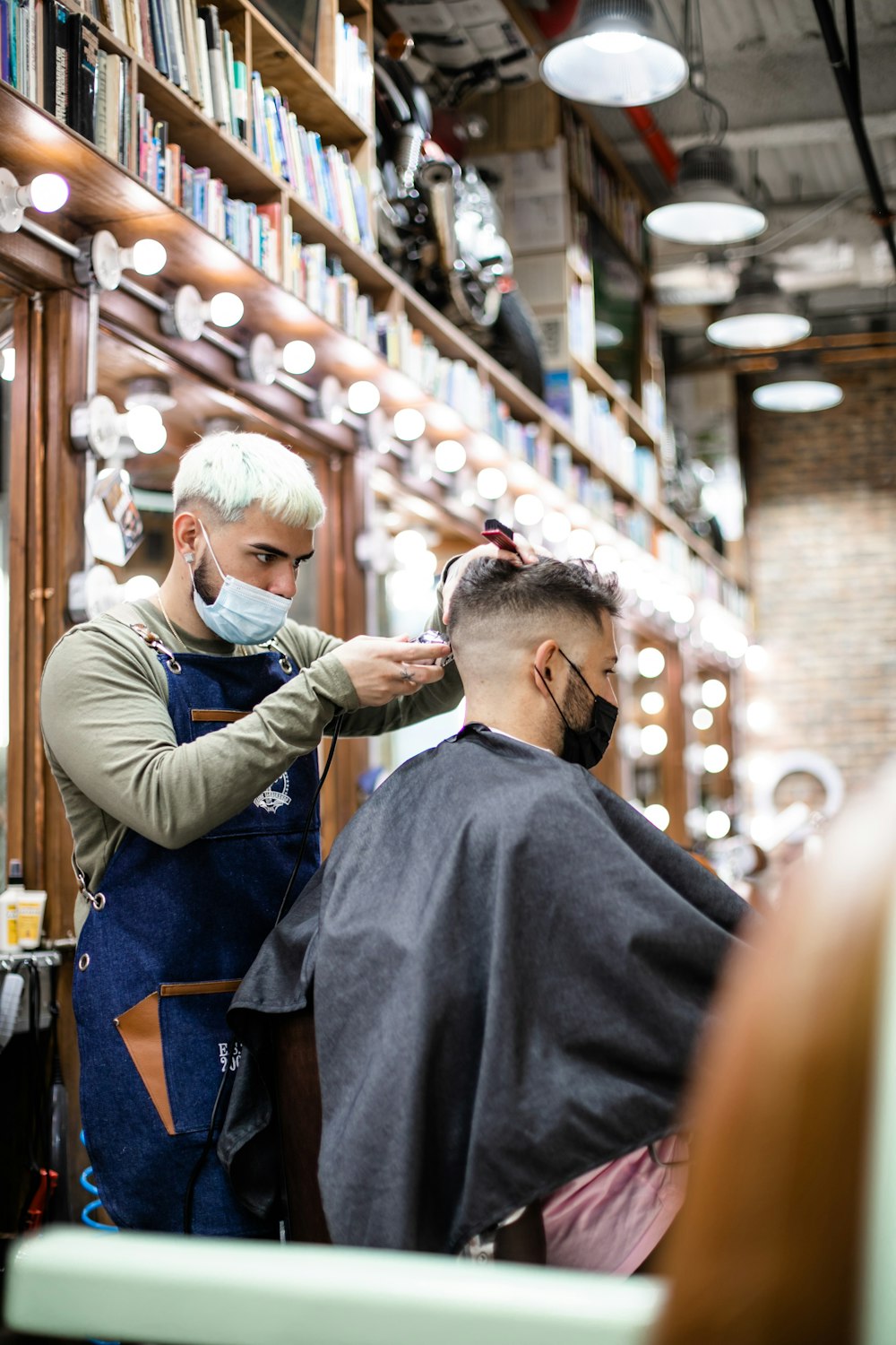 man in black long sleeve shirt cutting hair of man in black shirt