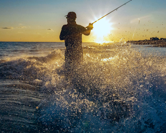 man in black jacket fishing on sea during daytime