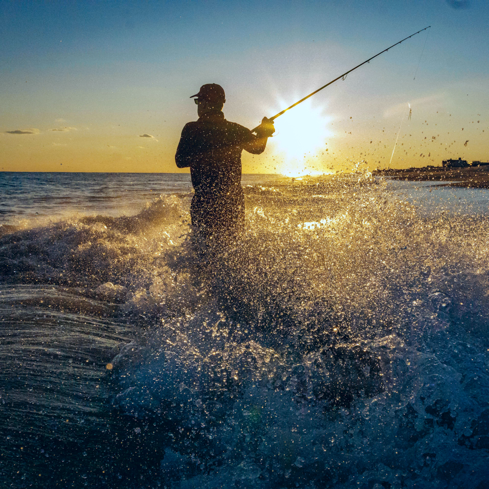 homem na pesca da jaqueta preta no mar durante o dia