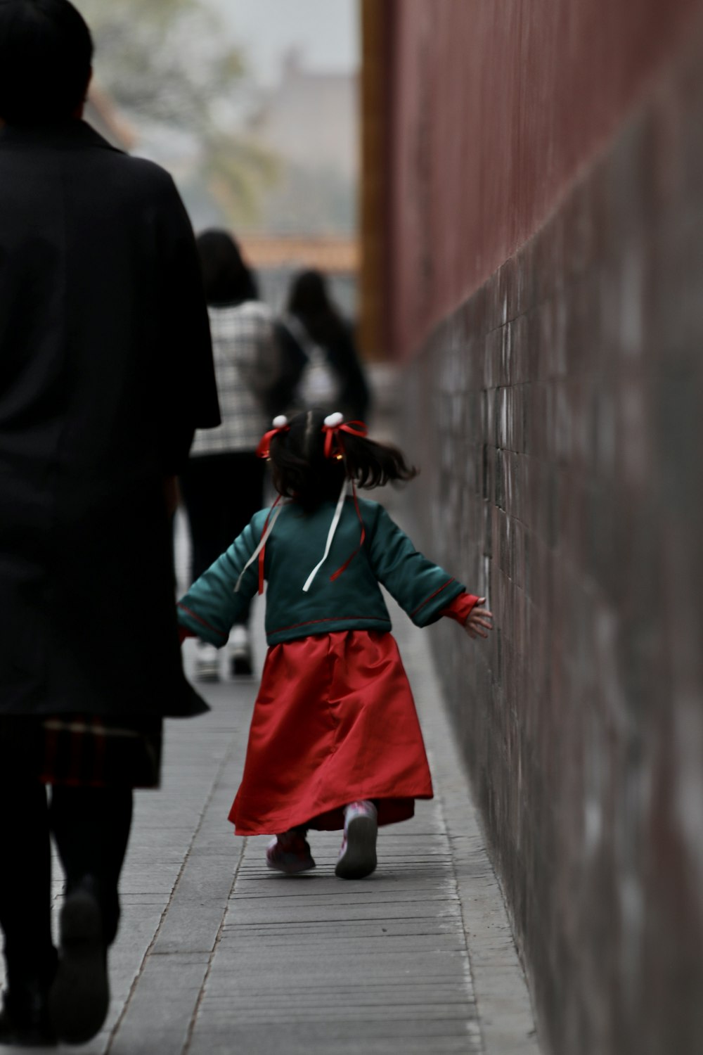 woman in green and red dress walking on gray concrete pathway