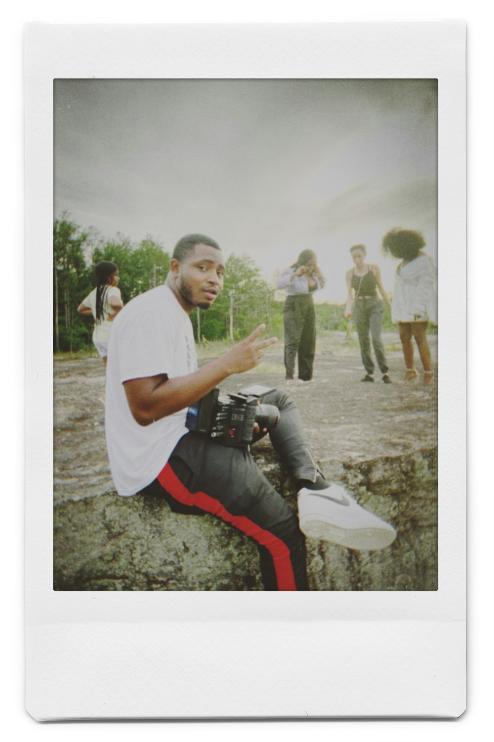 man in white t-shirt and red pants sitting on rock