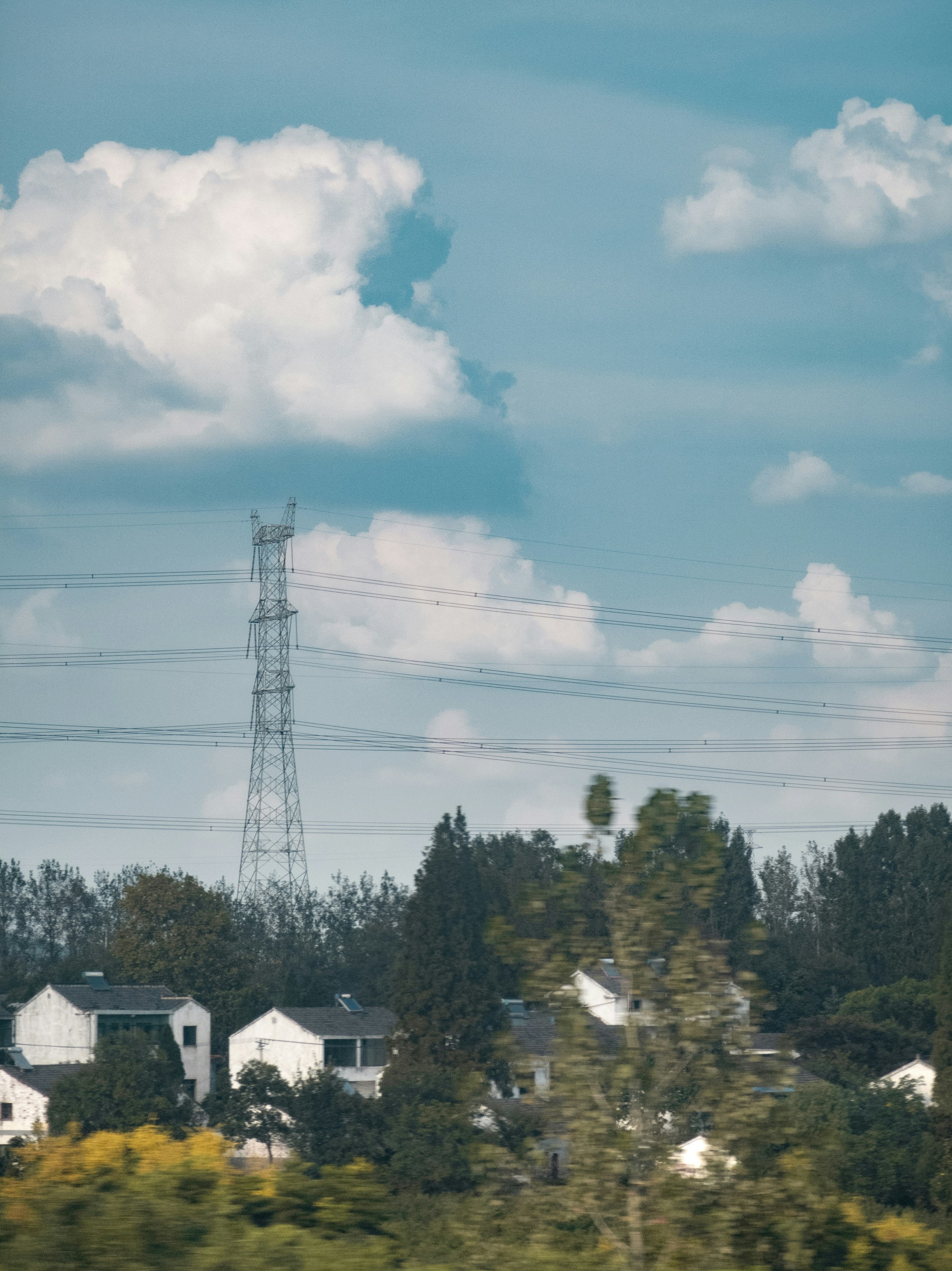Weißes und schwarzes Haus umgeben von grünen Bäumen unter weißen Wolken und blauem Himmel tagsüber