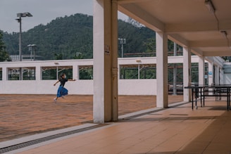 woman in blue shirt and blue denim jeans walking on brown wooden floor during daytime