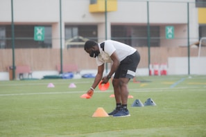 man in white shirt and black shorts playing soccer during daytime