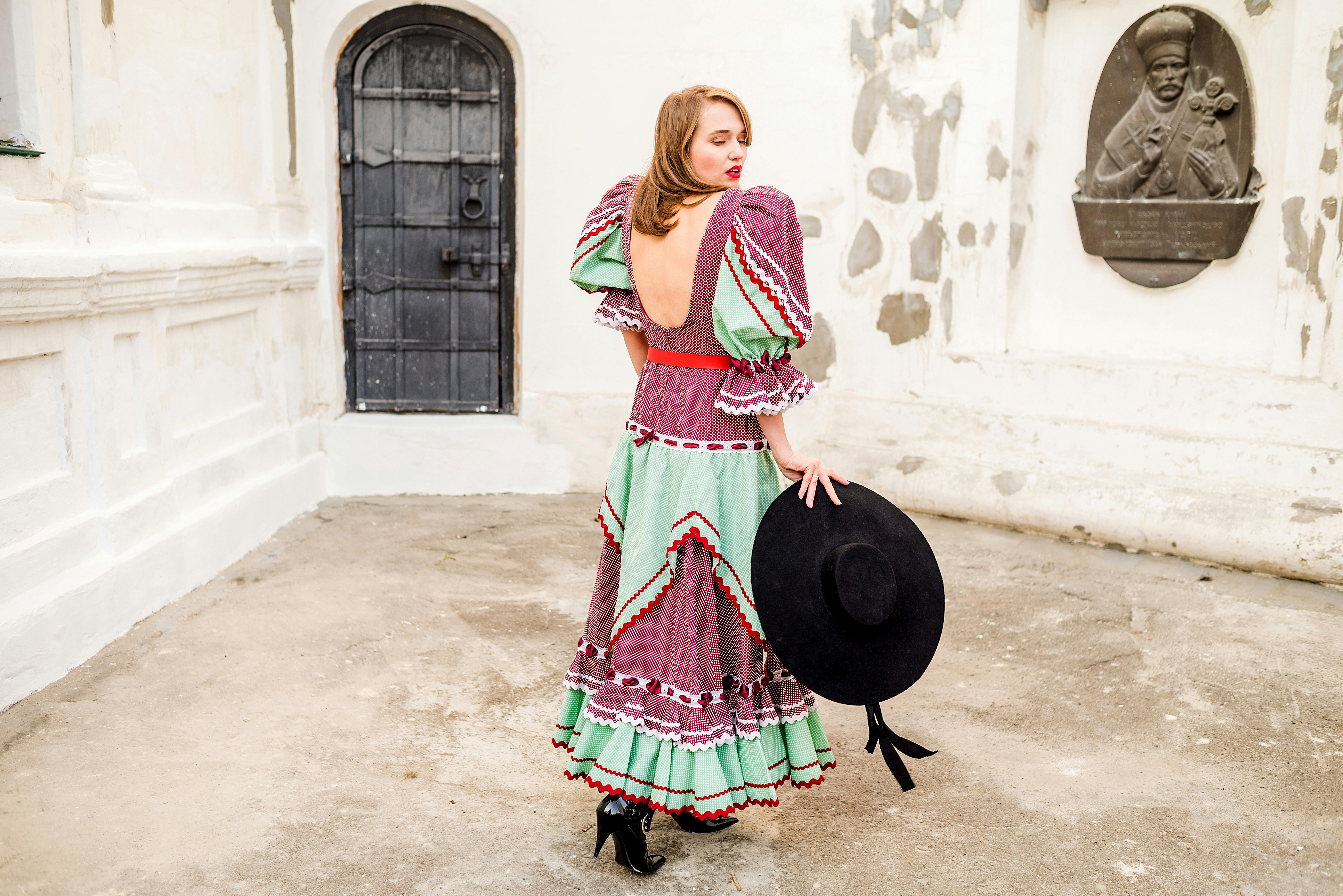 A woman in a traditional Andalusian flamenca dress holding a wide-brimmed hat, as worn at the Feria de Abril