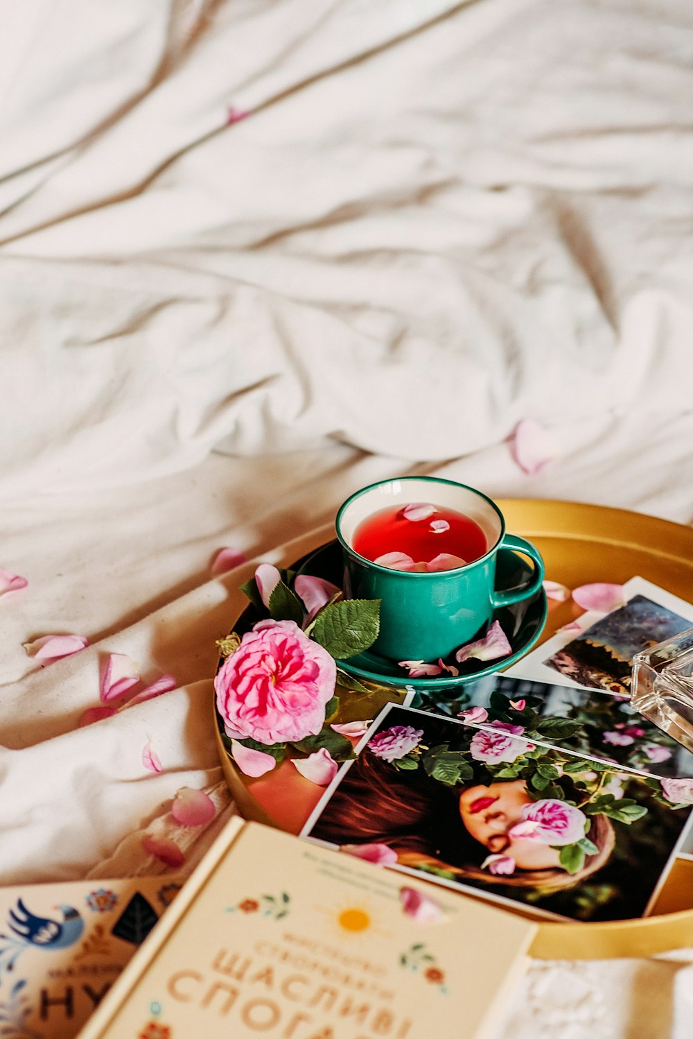 pink rose beside green ceramic mug on brown wooden tray