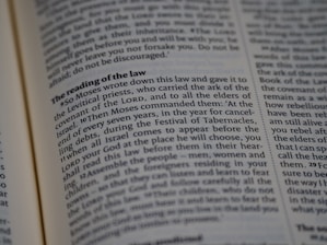 A close-up view of a page from a religious text, featuring printed paragraphs with a bold heading 'The reading of the law'. The text discusses instructions given by Moses about laws and the Festival of Tabernacles. The words are neatly aligned in columns.