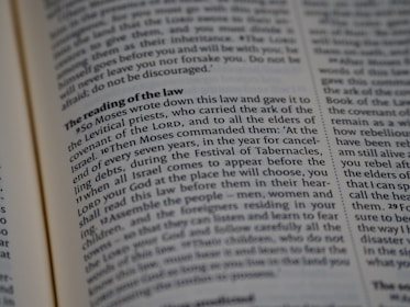 A close-up view of a page from a religious text, featuring printed paragraphs with a bold heading 'The reading of the law'. The text discusses instructions given by Moses about laws and the Festival of Tabernacles. The words are neatly aligned in columns.
