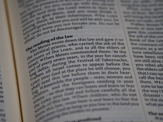 A close-up view of a page from a religious text, featuring printed paragraphs with a bold heading 'The reading of the law'. The text discusses instructions given by Moses about laws and the Festival of Tabernacles. The words are neatly aligned in columns.