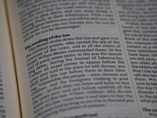 A close-up view of a page from a religious text, featuring printed paragraphs with a bold heading 'The reading of the law'. The text discusses instructions given by Moses about laws and the Festival of Tabernacles. The words are neatly aligned in columns.