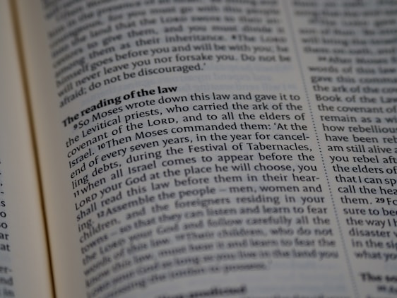 A close-up view of a page from a religious text, featuring printed paragraphs with a bold heading 'The reading of the law'. The text discusses instructions given by Moses about laws and the Festival of Tabernacles. The words are neatly aligned in columns.