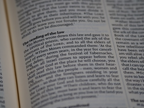 A close-up view of a page from a religious text, featuring printed paragraphs with a bold heading 'The reading of the law'. The text discusses instructions given by Moses about laws and the Festival of Tabernacles. The words are neatly aligned in columns.