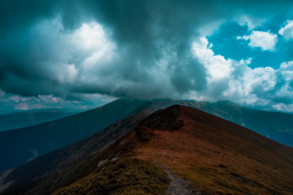 brown and green mountain under white clouds and blue sky during daytime