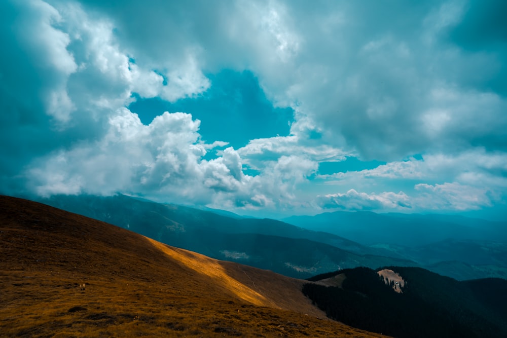 brown and green mountain under white clouds and blue sky during daytime