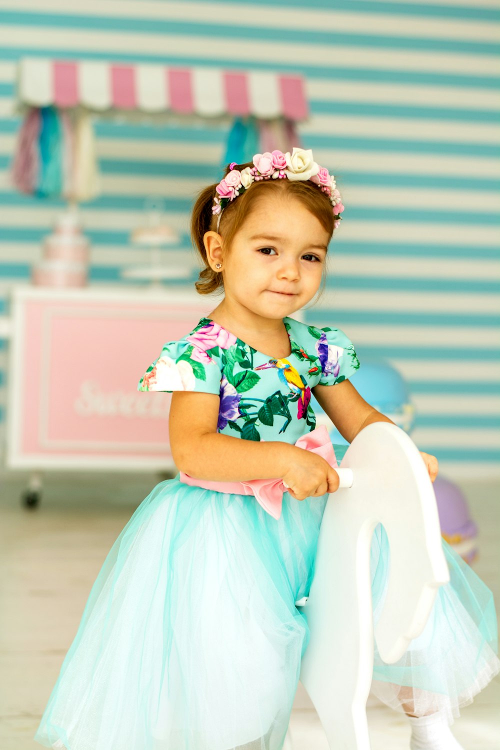 girl in pink and white floral dress sitting on white chair