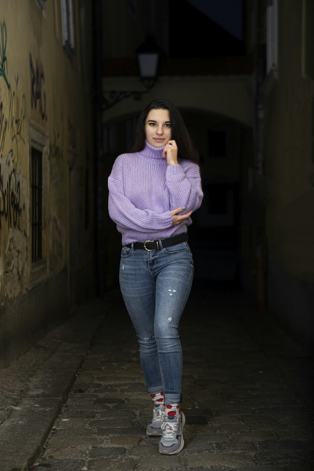 Frau in lila Pullover und blauer Jeans auf Flur