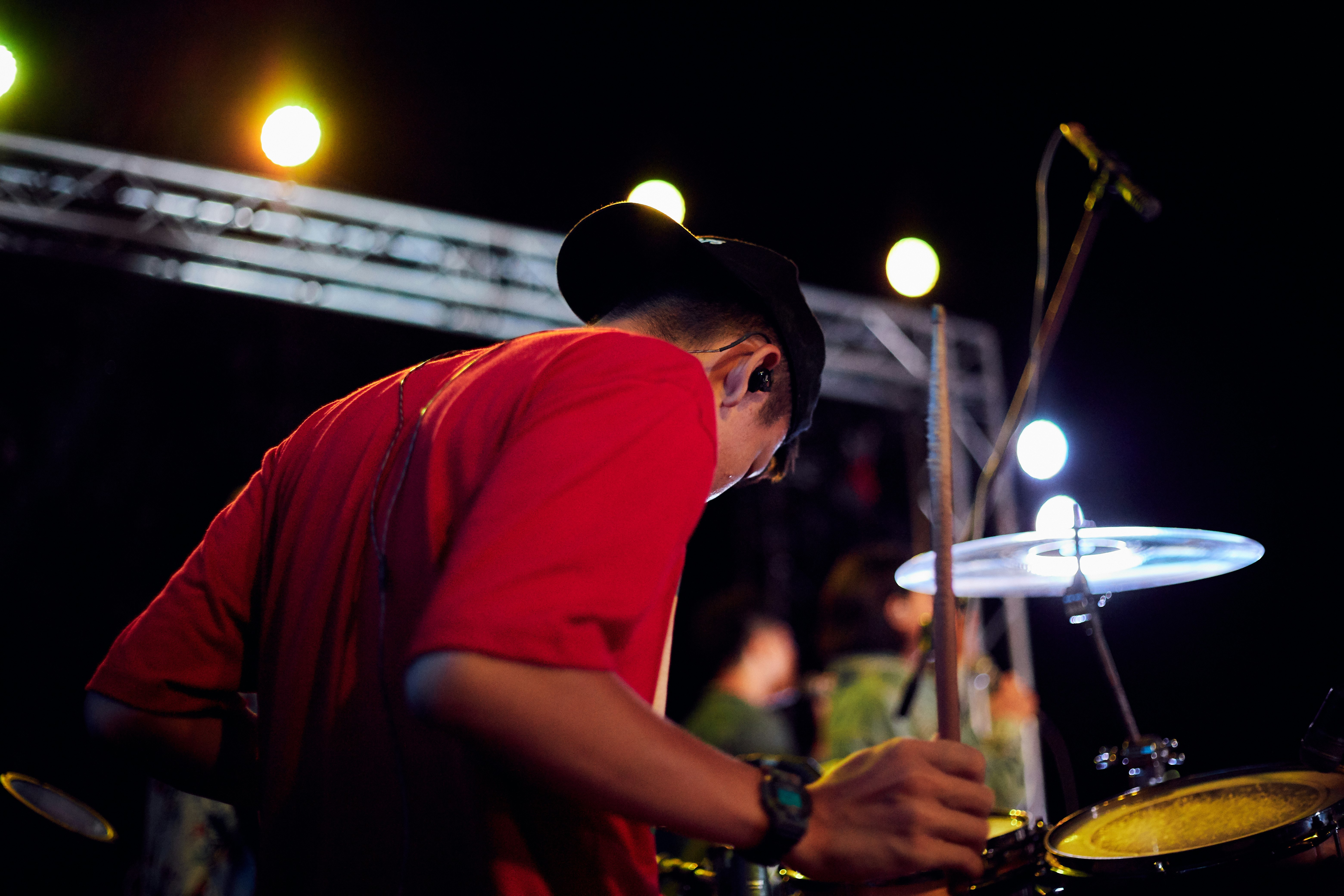 man in red crew neck t-shirt playing drum set during night time