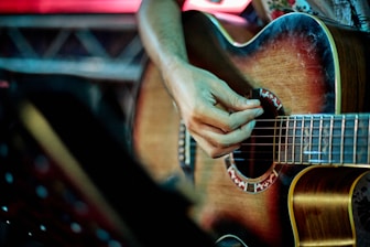 person playing brown acoustic guitar