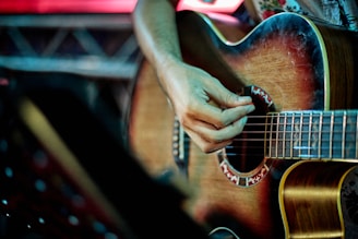 person playing brown acoustic guitar