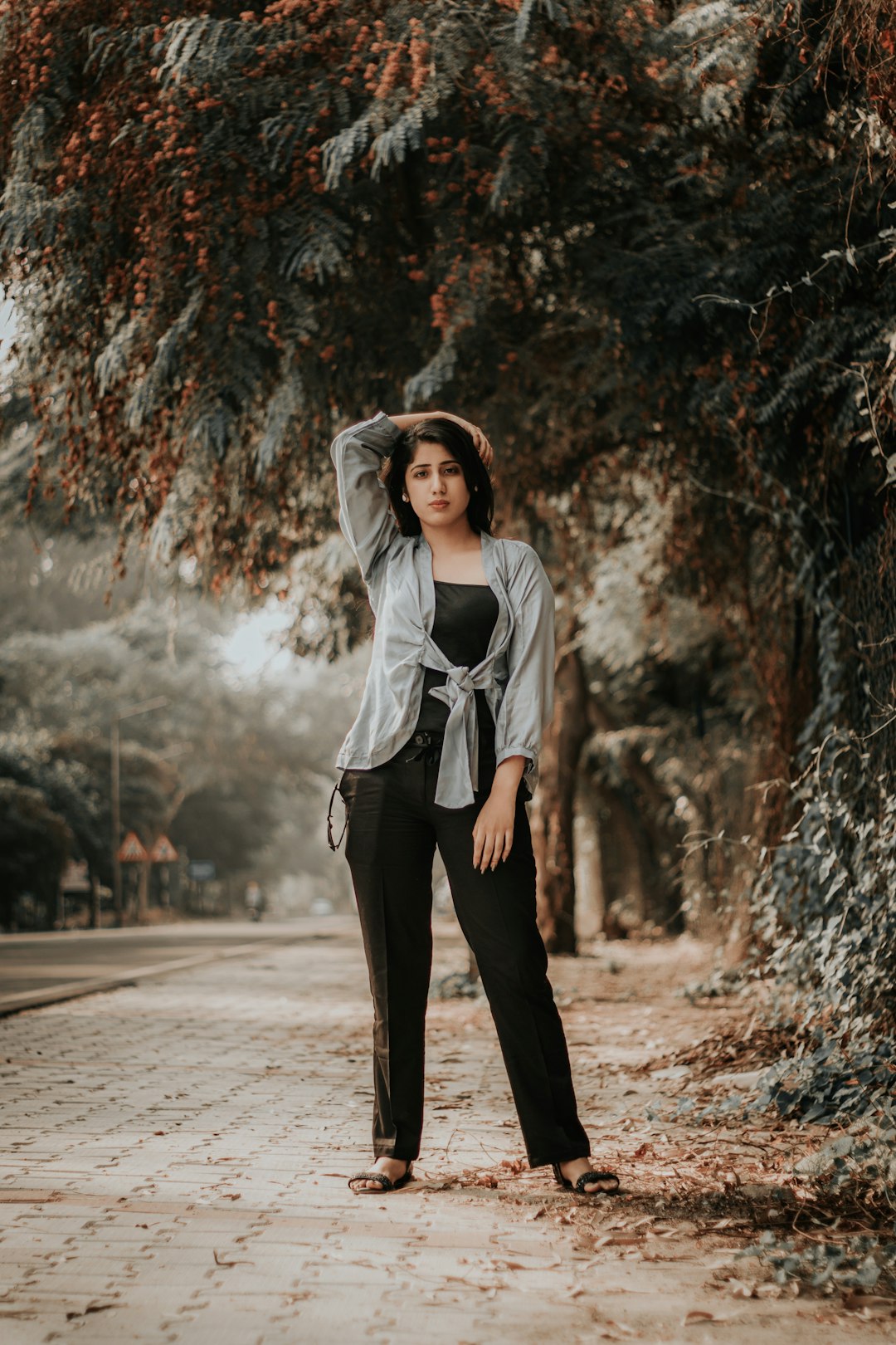 woman in gray long sleeve shirt and black pants standing on gray sand during daytime