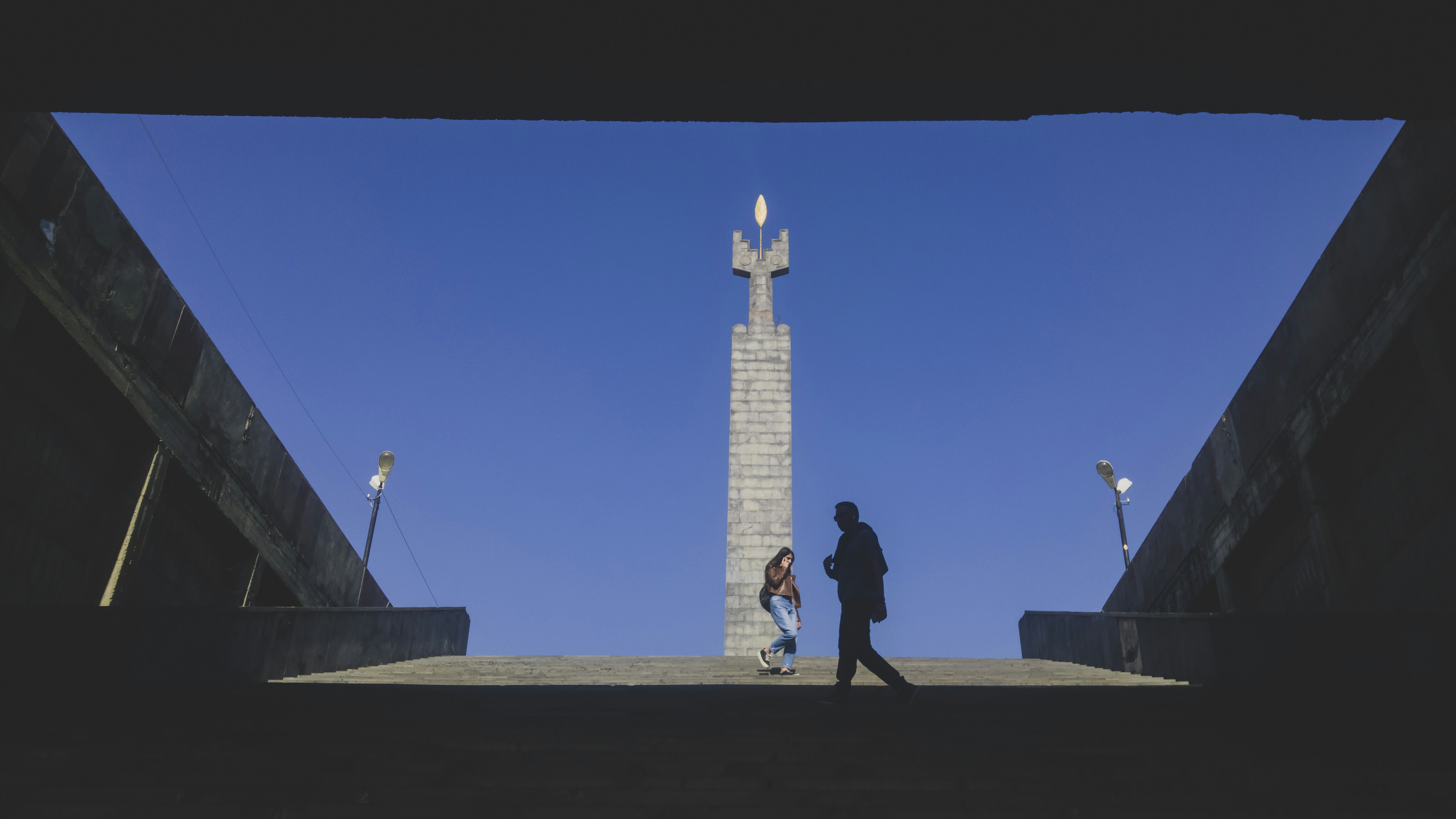 people walking on gray concrete pathway near white concrete tower during daytime