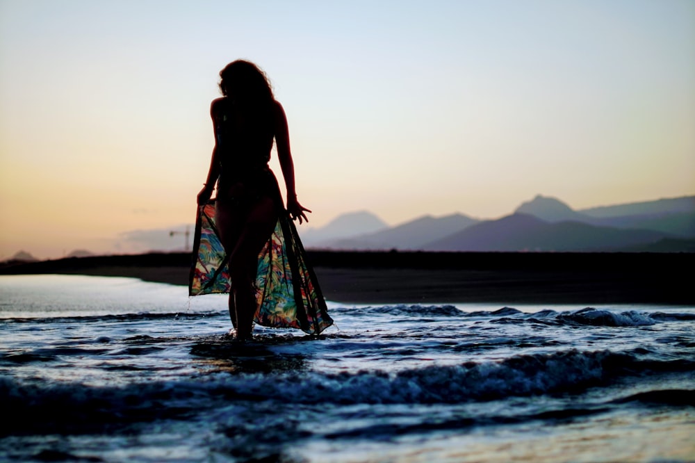 woman in black tank top standing on beach during sunset