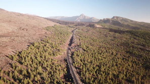 A wide aerial view of a newly constructed highway cutting through rugged Afghan terrain under a clear sky.