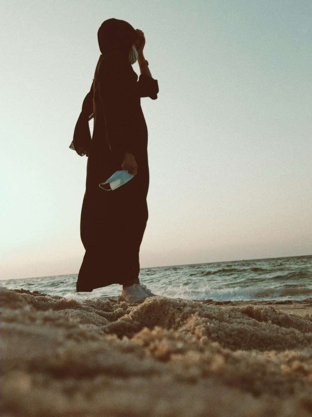 woman in black dress standing on seashore during daytime