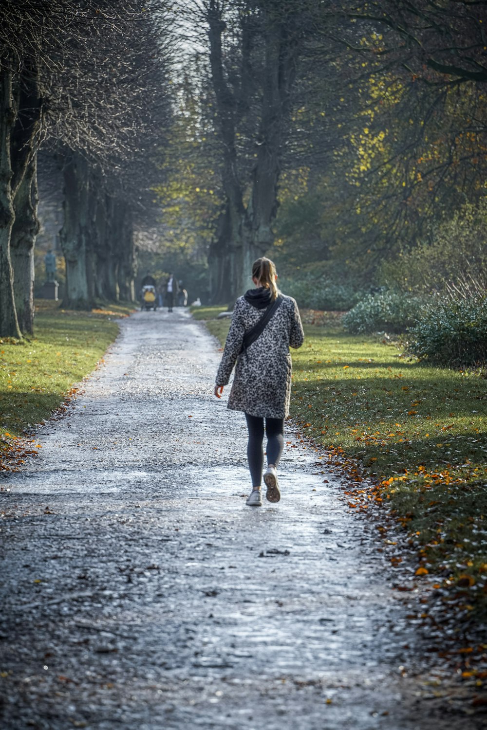 woman in black and white polka dot coat walking on pathway