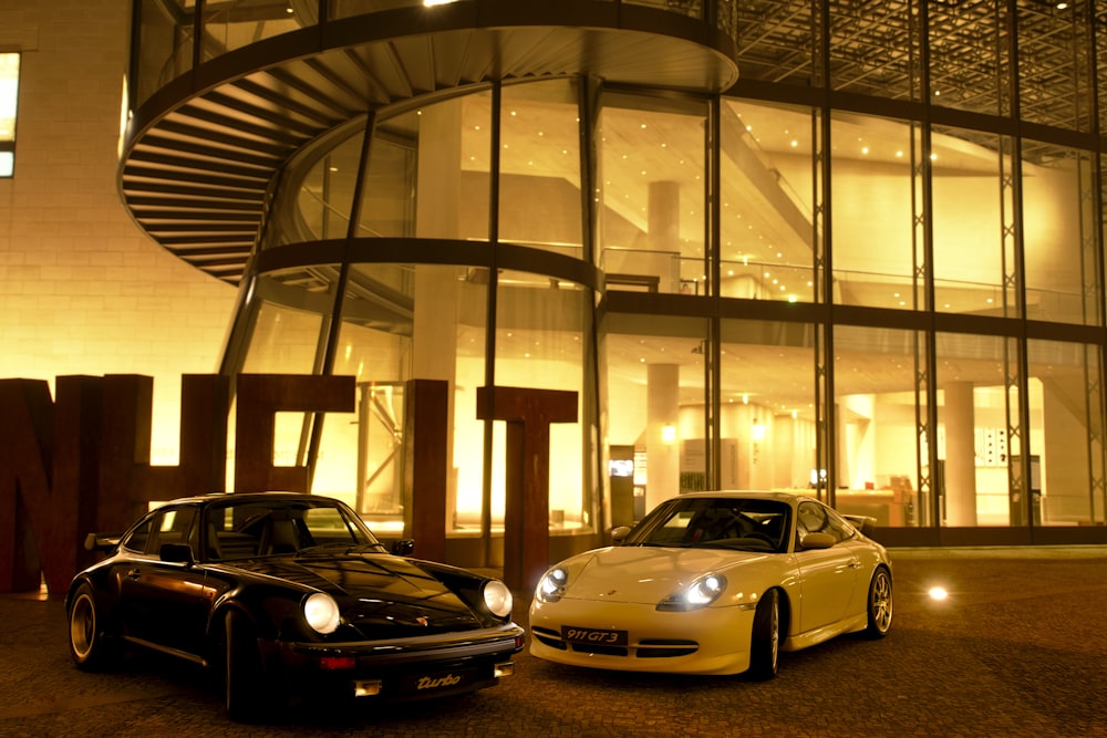 yellow and black porsche 911 parked in front of glass building