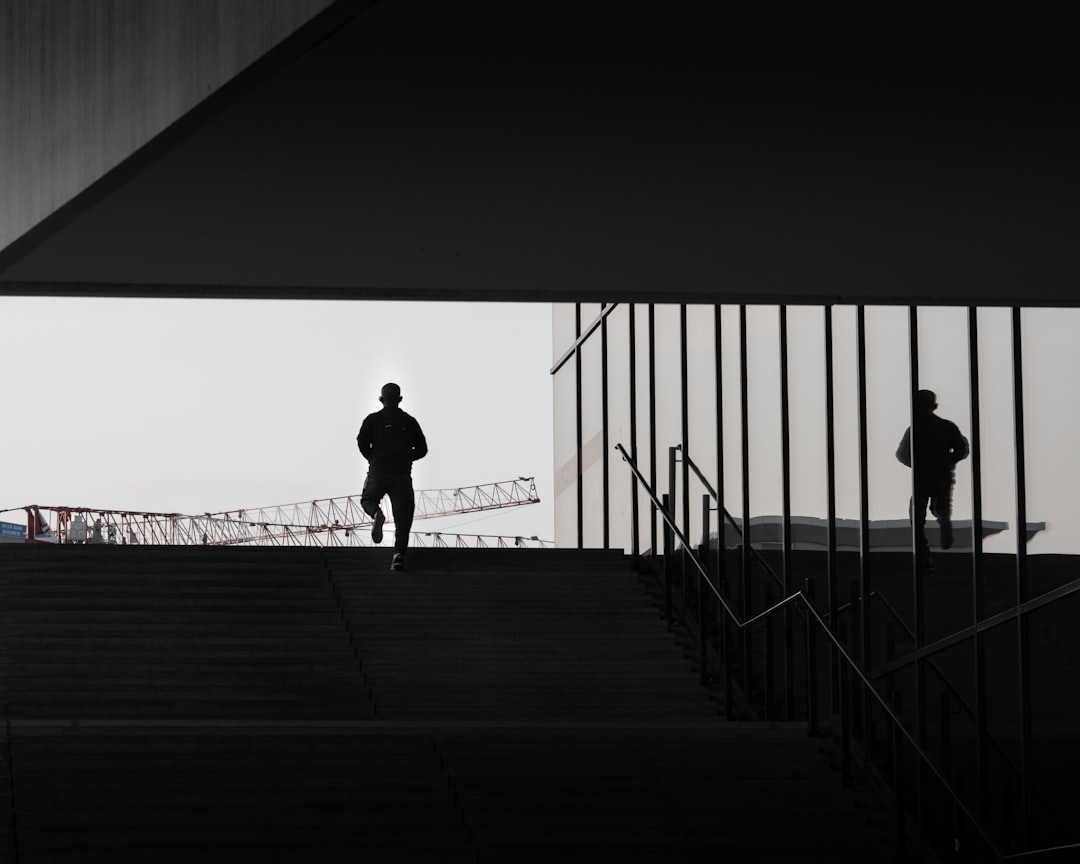 silhouette of man walking on wooden bridge