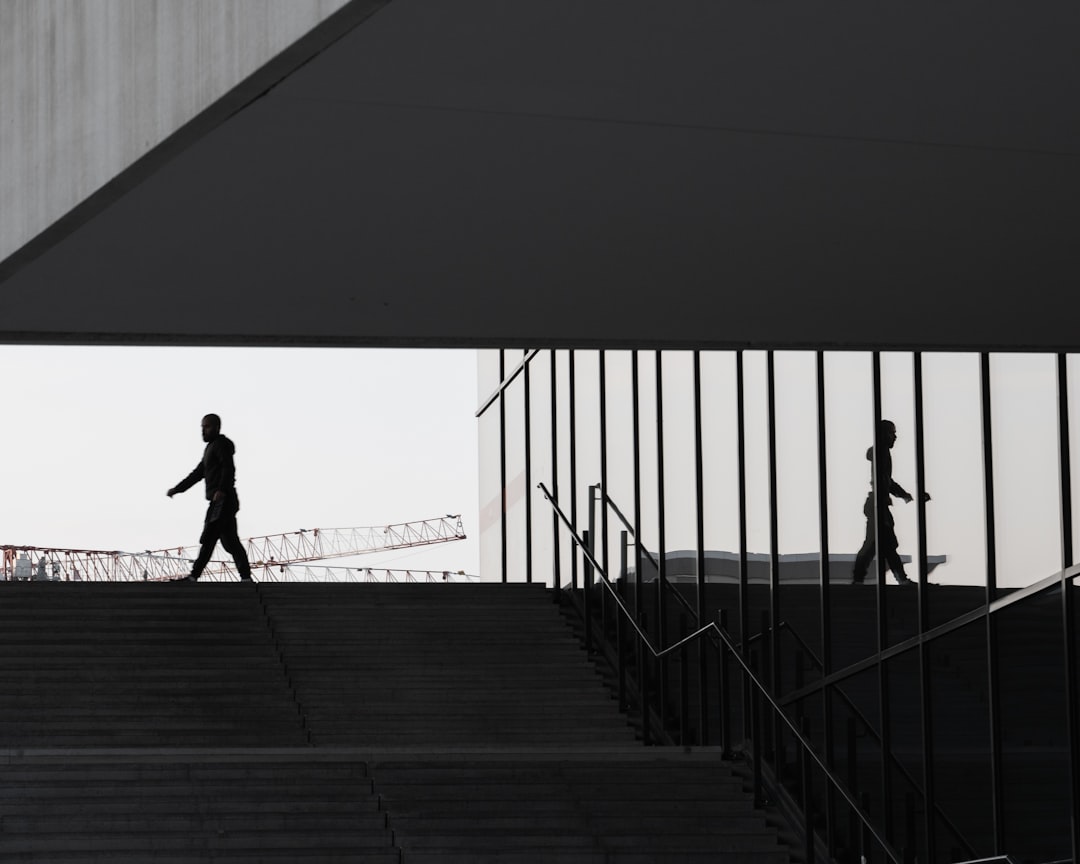 silhouette of man walking on wooden bridge