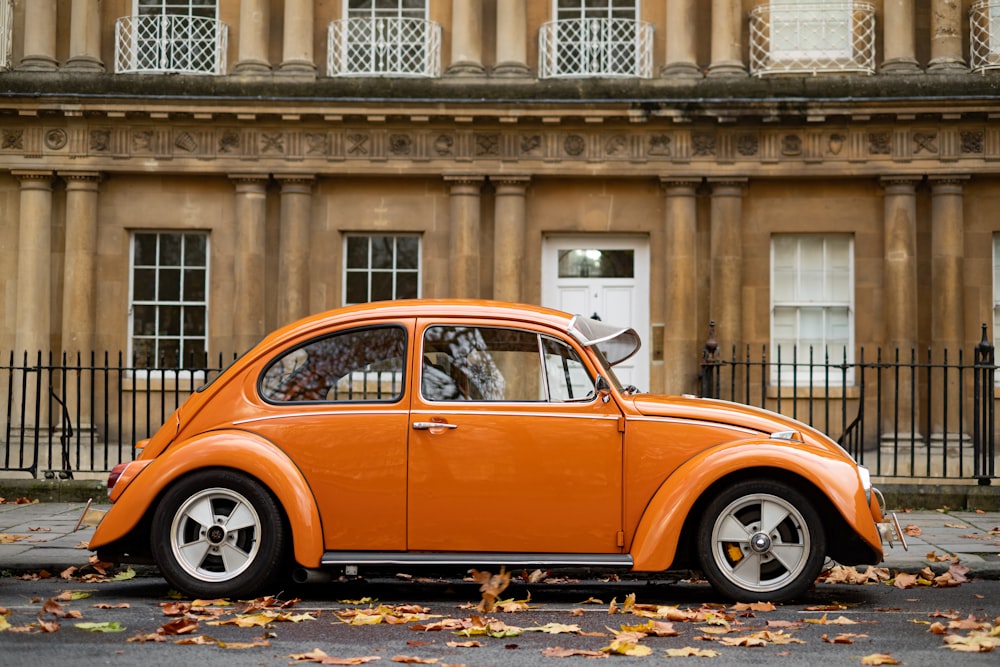 orange volkswagen beetle parked near building