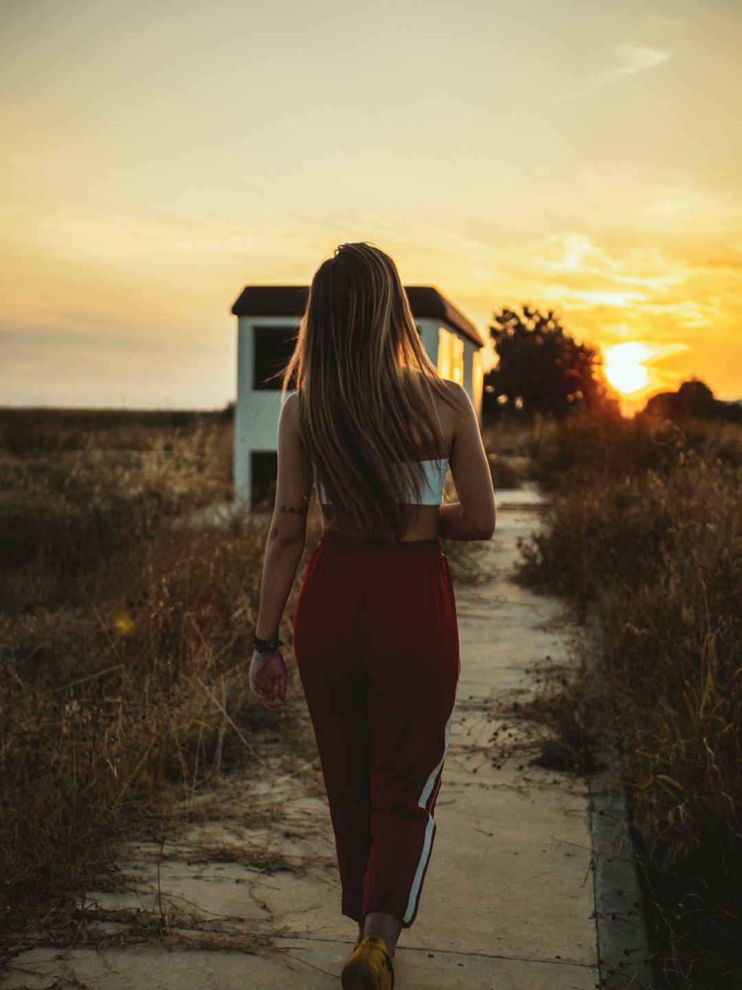 woman in gray tank top and black pants standing on green grass field during sunset