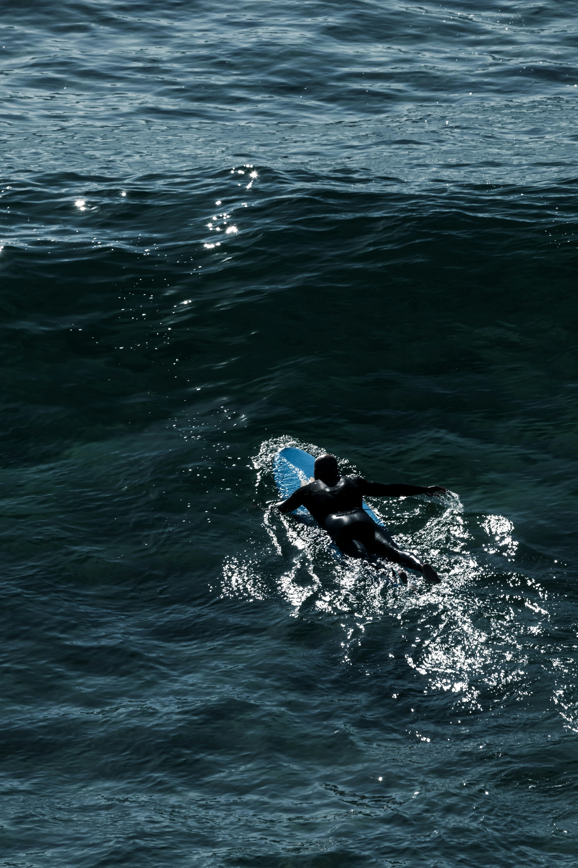 昼間に青い海の水でサーフィンする黒いウェット スーツの男の写真 Unsplashで見つける黒の無料写真