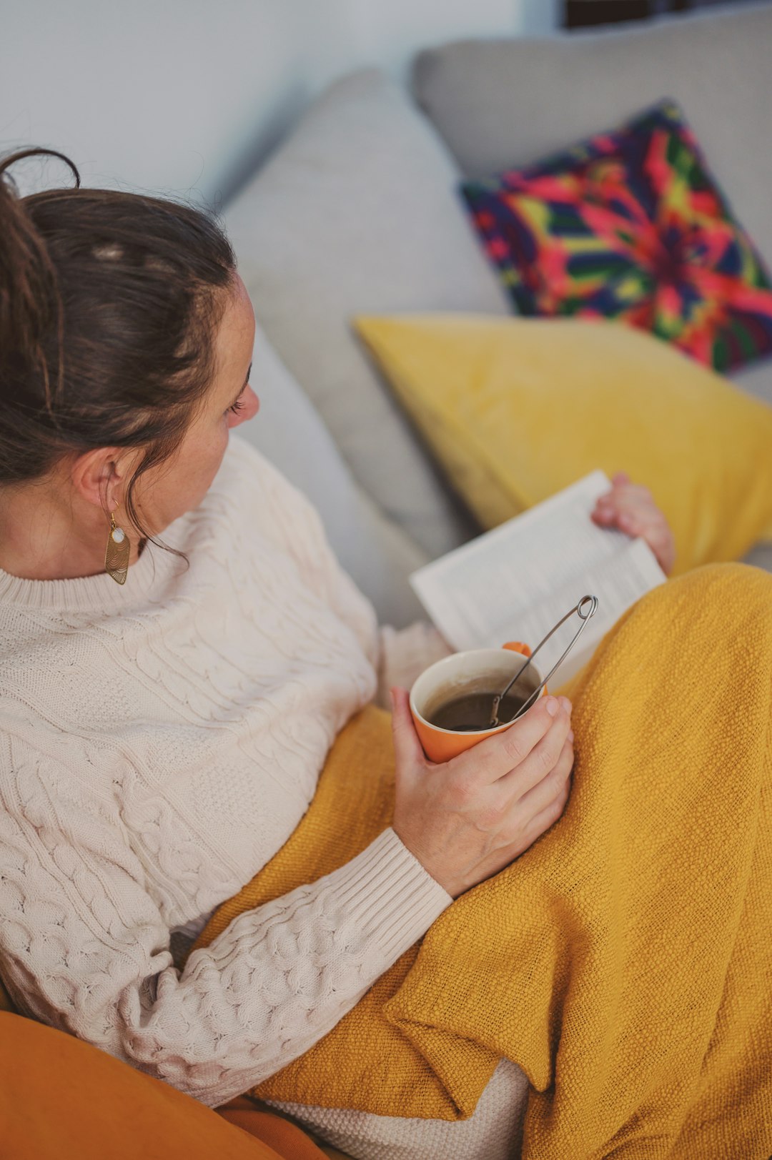 woman in white knit sweater holding white ceramic mug