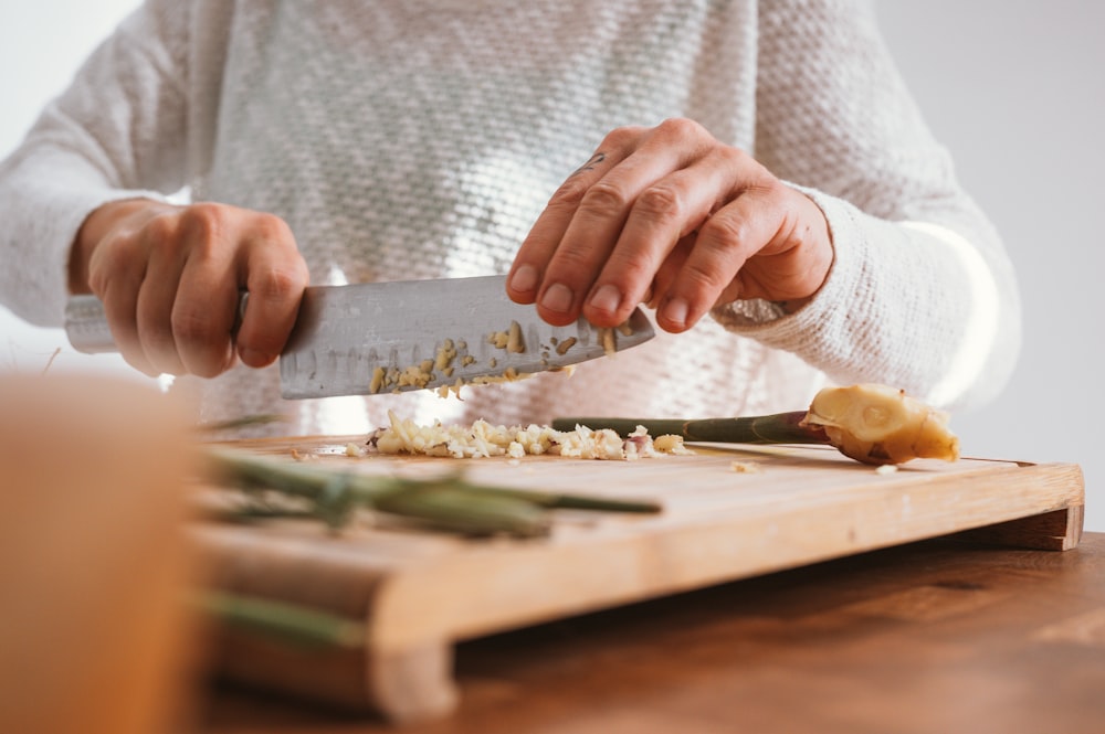 person holding knife slicing vegetable