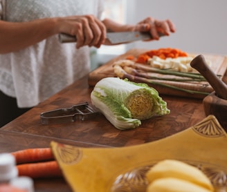 person slicing green vegetable on brown wooden chopping board