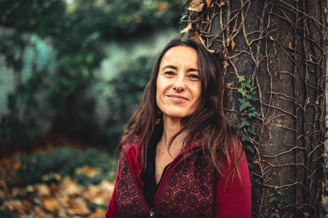 woman in red and black floral robe standing beside brown tree