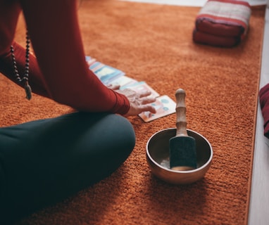 person in teal pants sitting on floor with black round ceramic bowl